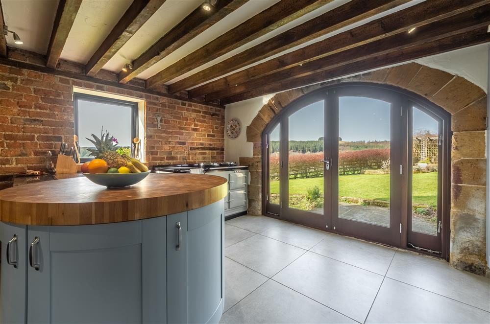 Kitchen with circular island and arched doorway to garden at Five Acres, Boltby