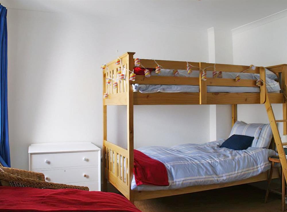 Comfortable bedroom with bunk bed and single bed at Flat 4, Trelawney Court in Rock, Cornwall