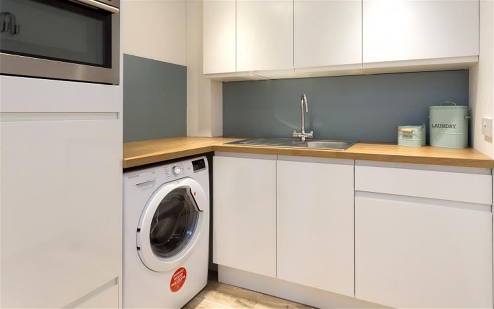 Utility room with washing machine, sink, freezer and additional fitted oven/grill appliance