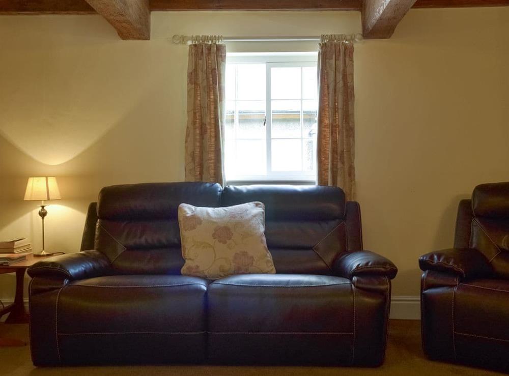 Spacious living room with exposed wood beams at Burdett’s Cottage, 