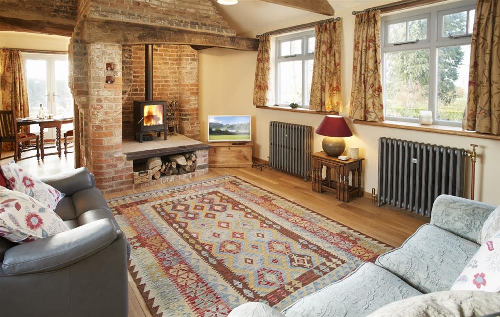 Sitting room with comfortable sofas, television and wood burning stove set in the original blacksmith’s forge