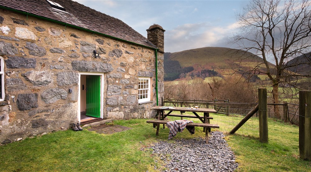 The back garden with picnic bench and valley views at Fron Dirion in Dinas Mawddwy, Powys
