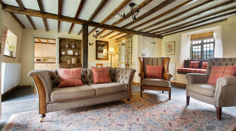 The sitting room with wood beams, sofas, armchairs and window seats at Fron Dirion in Dinas Mawddwy, Powys