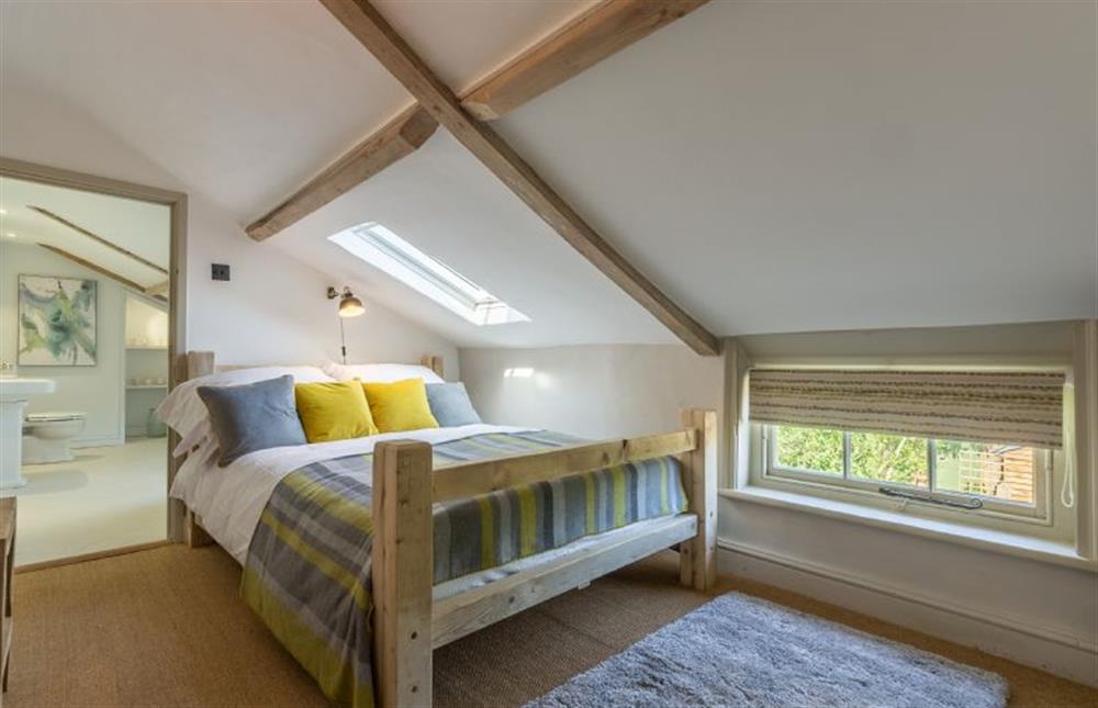 First floor:  Bedroom two with double bed with wooden frame at Gamekeepers Lodge, South Raynham near Fakenham