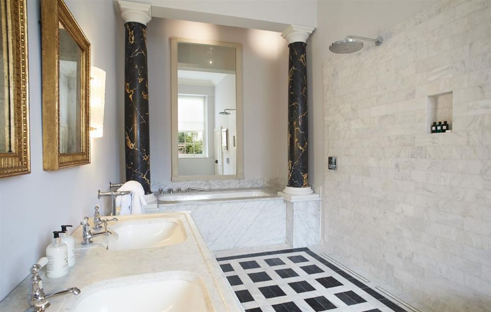 Bedroom one’s large marble en-suite bathroom with bath, rain shower and twin wash basins at Garden House, Wolterton