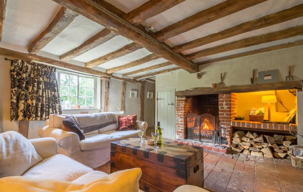 Sitting room with exposed beams and open fire at Gardeners Cottage (Suffolk), Thornham Magna