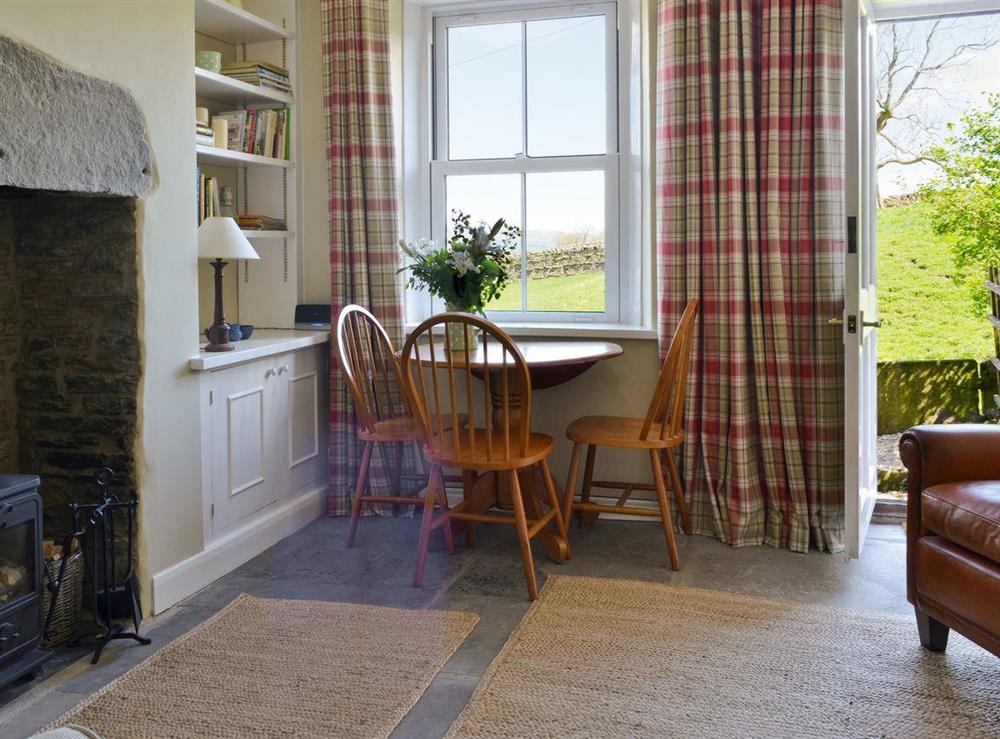 Living room with wood-burner and door to garden at Gardenwell Cottage in Burtersett, near Hawes, North Yorkshire
