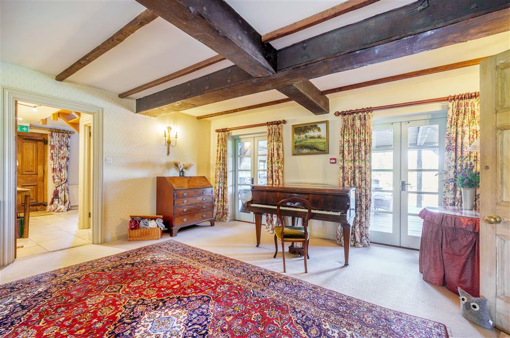 Traditional furnishings and a grand piano add character to the sitting room at Gate Street Farm House, Bramley, Guildford