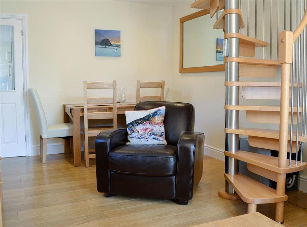 Living/dining area with spiral staircase at Ghillie Cottage in Cockermouth, Cumbria