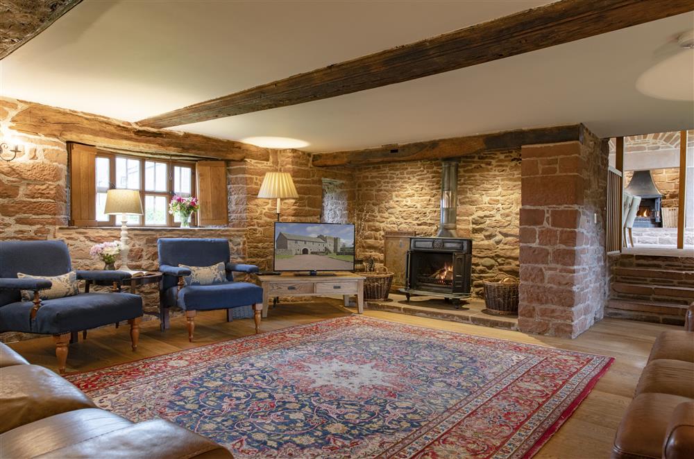 Spacious sitting room with exposed beams and stonework and cast iron wood burning stove at Glassonby Old Hall and Jennys Croft, Glassonby