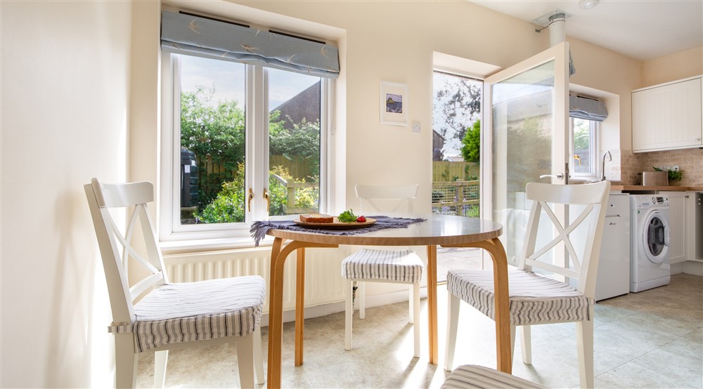 The open-plan kitchen and dining room with table and chairs for four, washing machine and tumble dryer at Glen House in Berwick-upon-tweed, Northumberland
