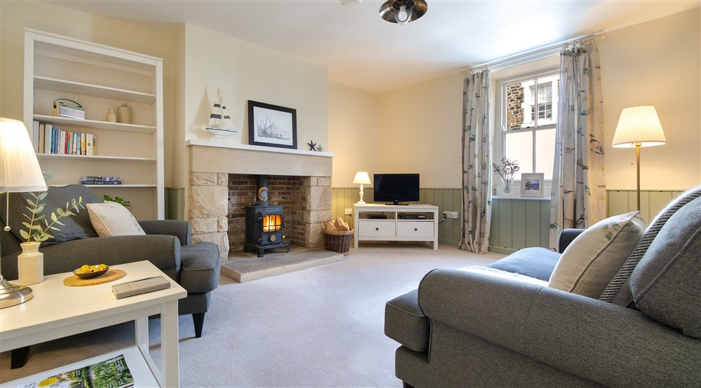 The sitting room with sofa, armchair, television and wood burning stove at Glen House in Berwick-upon-tweed, Northumberland