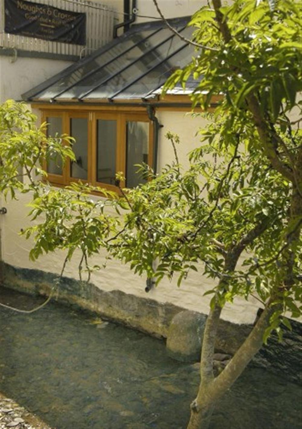The delightful rear of conservatory with the river Pol running alongside at Glencoe Cottage in Polperro