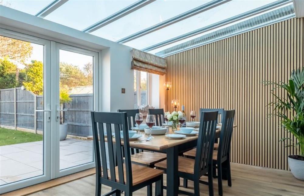 Dining area with seating for six, glass roof and french doors leading to an enclosed garden at Golf Cottage, West Runton near Cromer