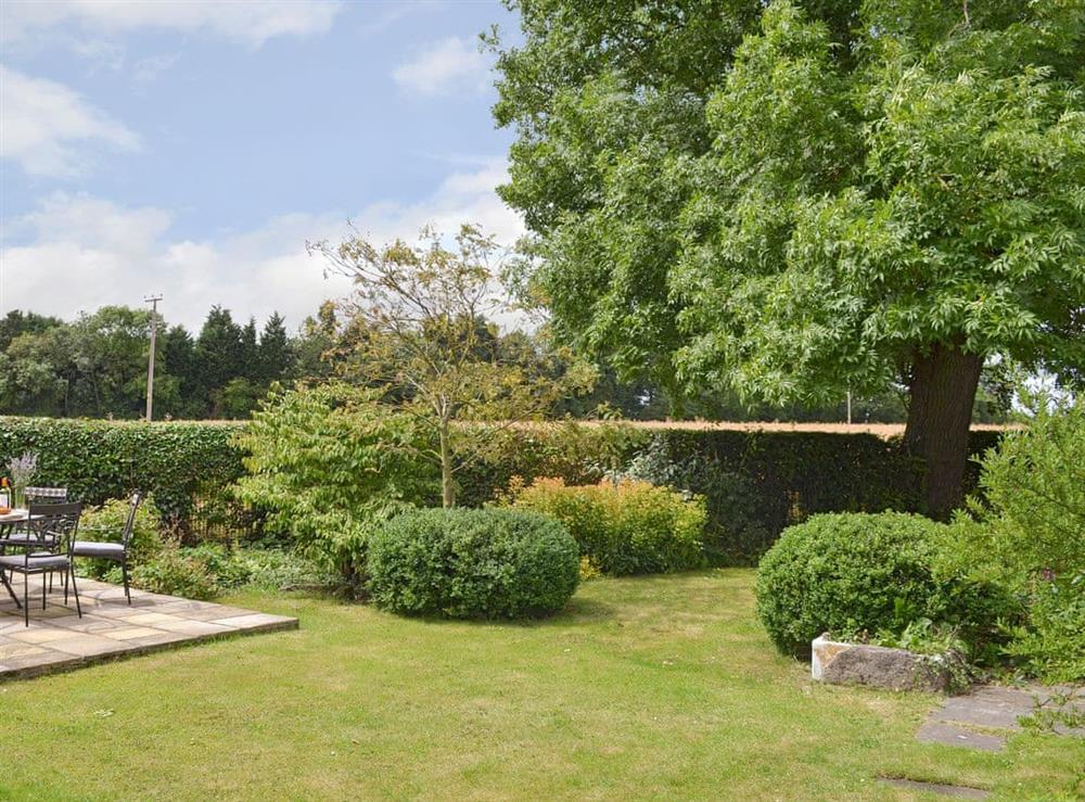 Enclosed lawned garden with patio area at Portington Lodge, 