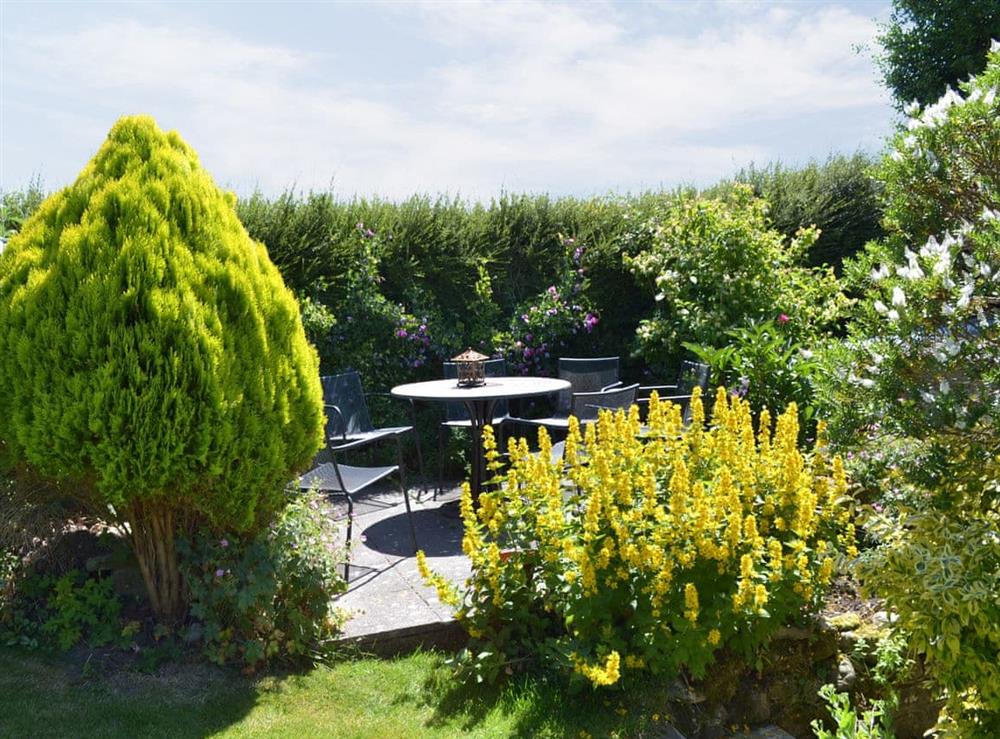 Delightful gardens with paved area with table and chairs for alfresco dining at Grange Fell in Grange-over-Sands, Cumbria