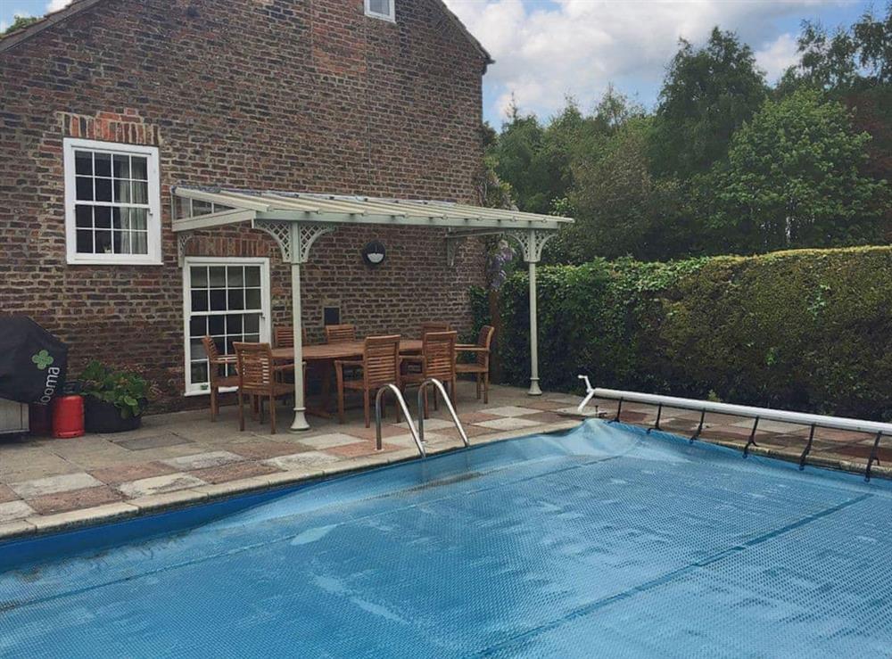 Outdoor solar panel heated swimming pool with BBQ and sitting out areas at Greenlands Farmhouse in Barmby Moor, York., North Yorkshire