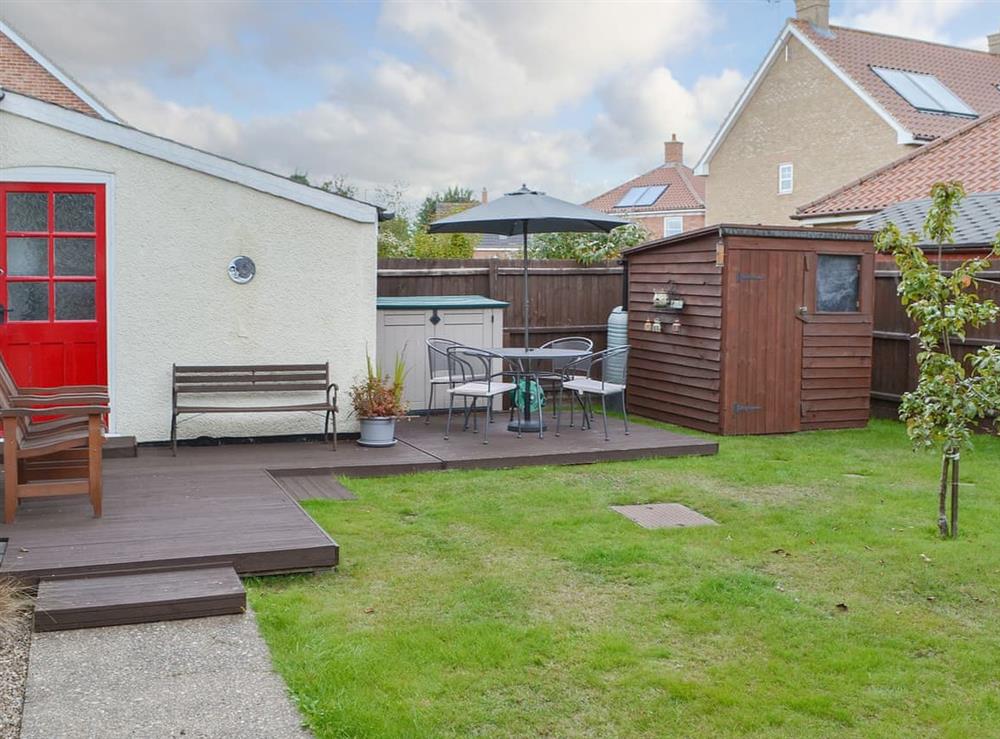 Lawned garden with decked area and table and chairs at Half Moon Cottage in Great Yarmouth, Norfolk