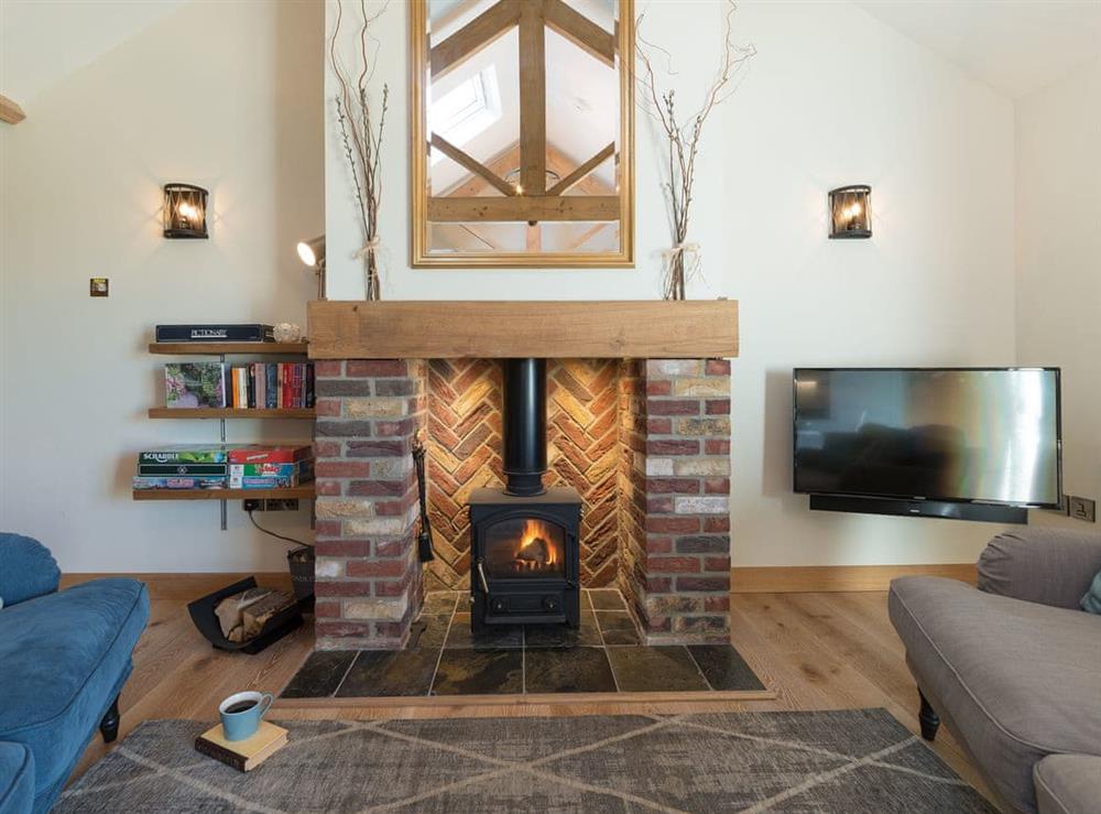Open plan living with multi-fuel burner & wood beams at Daisy Cottage, 