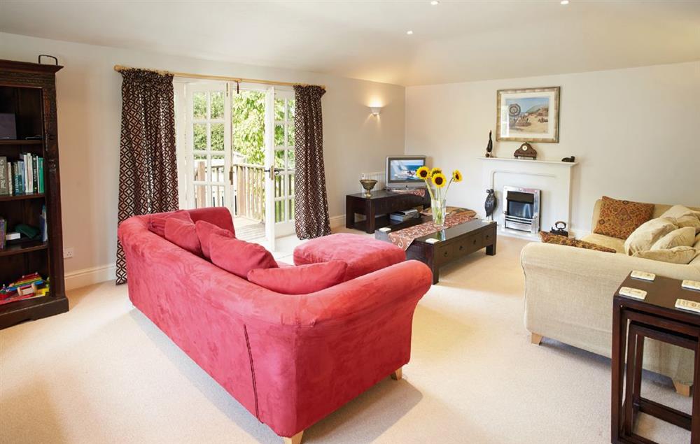 Principal sitting room with French doors opening onto a deck overlooking the garden at Hamilton House, Branscombe