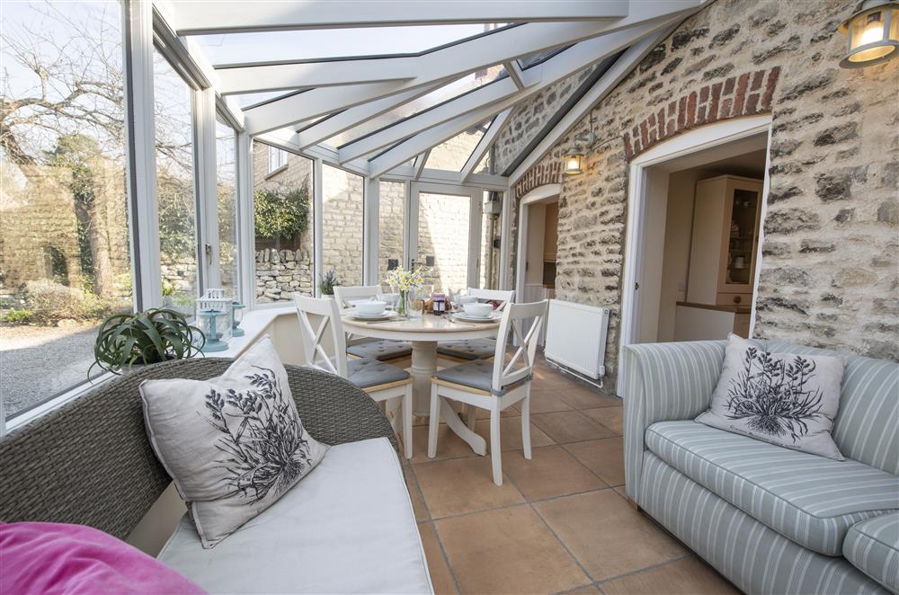 Conservatory with relaxed seating and dining area at Harwood Cottage, Hovingham