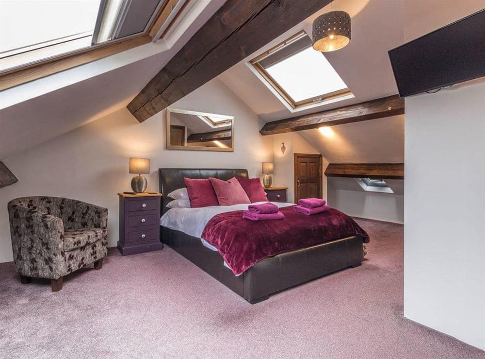 Beamed bedroom with leather bed at Havelock Cottage in Windermere, Cumbria