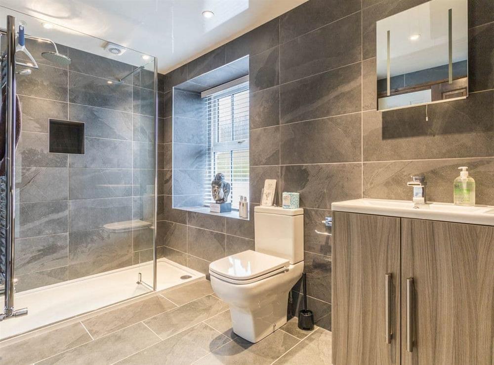 Shower room with walk-in shower, floor to ceiling tiles and heated towel rail at Havelock Cottage in Windermere, Cumbria