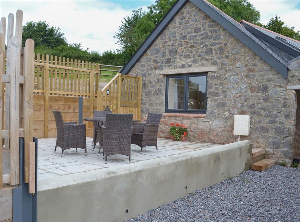 Raised paved patio with table and chairs at Scrumpy Barn, 