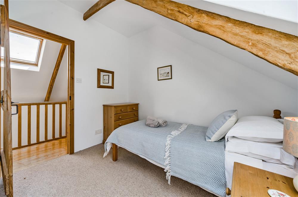 Bedroom three, with view out to the hallway and continuous wooden beams at Hayloft Cottage, Totnes