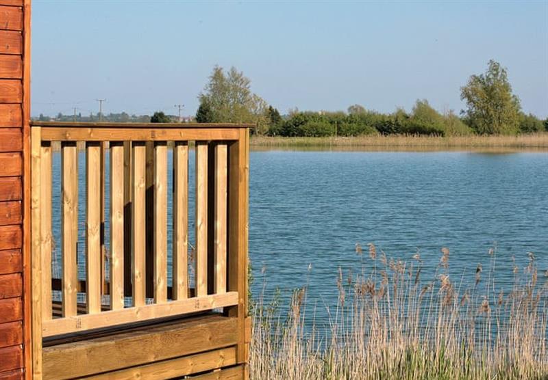 Lodges have a decking area looking over the lake at Head Fen Country Retreat in Ely, Cambridge