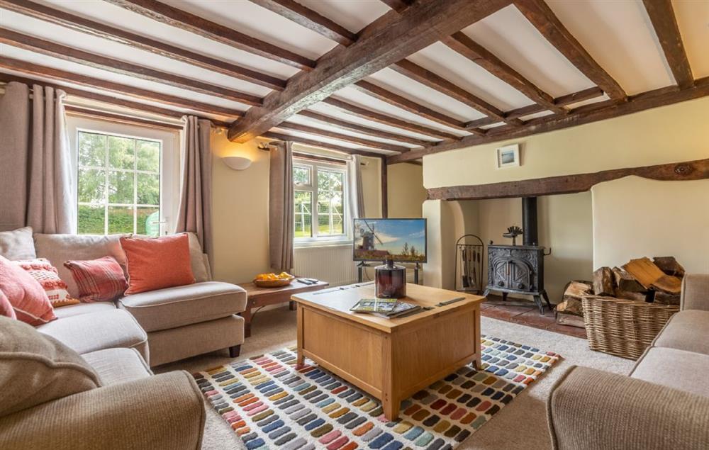 Sitting room with wood burning stove and original beams at Heath Cottage, Mattishall