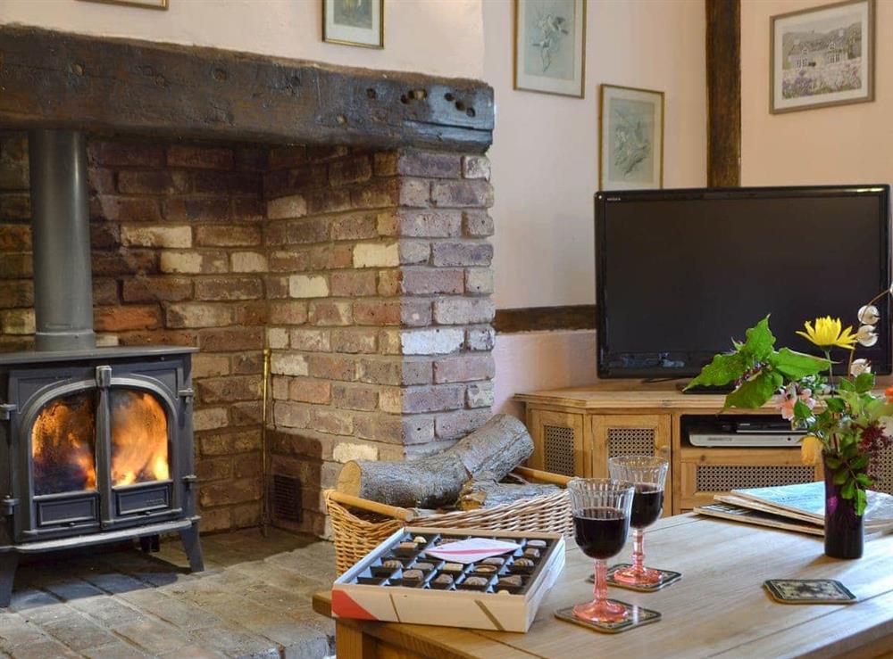 Warm and welcoming inglenook fireplace with wood burner at Henley Bridge Holiday Cottage in Ashburnham, near Battle, East Sussex