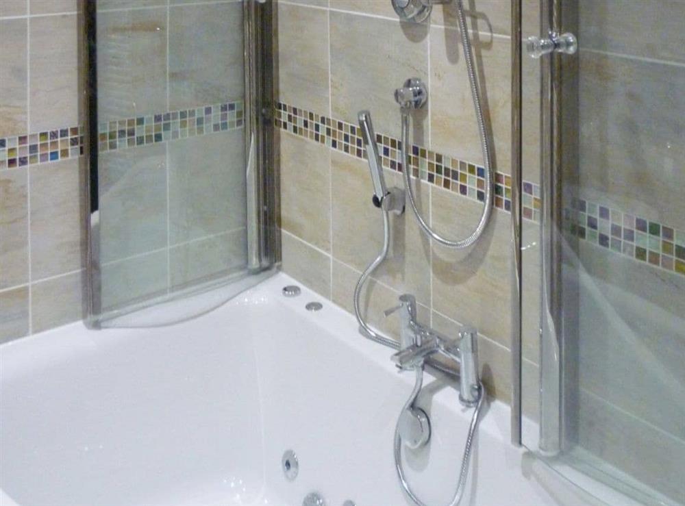Corner spa bath with overbath shower at Hertsmerry Cottage in Sidestrand, near Cromer, Norfolk