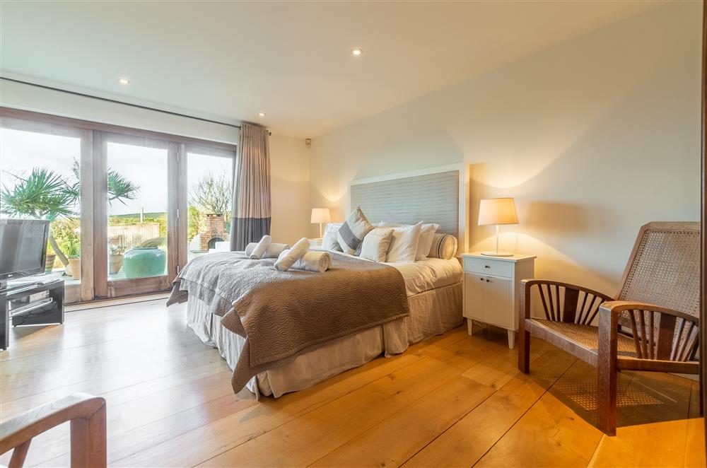 Bedroom with 5’ king-size bed, en-suite bathroom and bi-fold doors to the terrace at Higher Close, Mawgan Porth