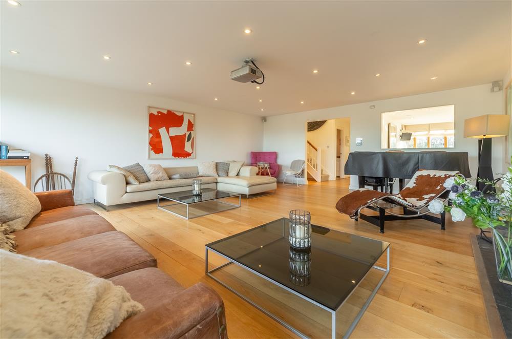 Open-plan living area with large comfortable sofas and a wood burning stove at Higher Close, Mawgan Porth