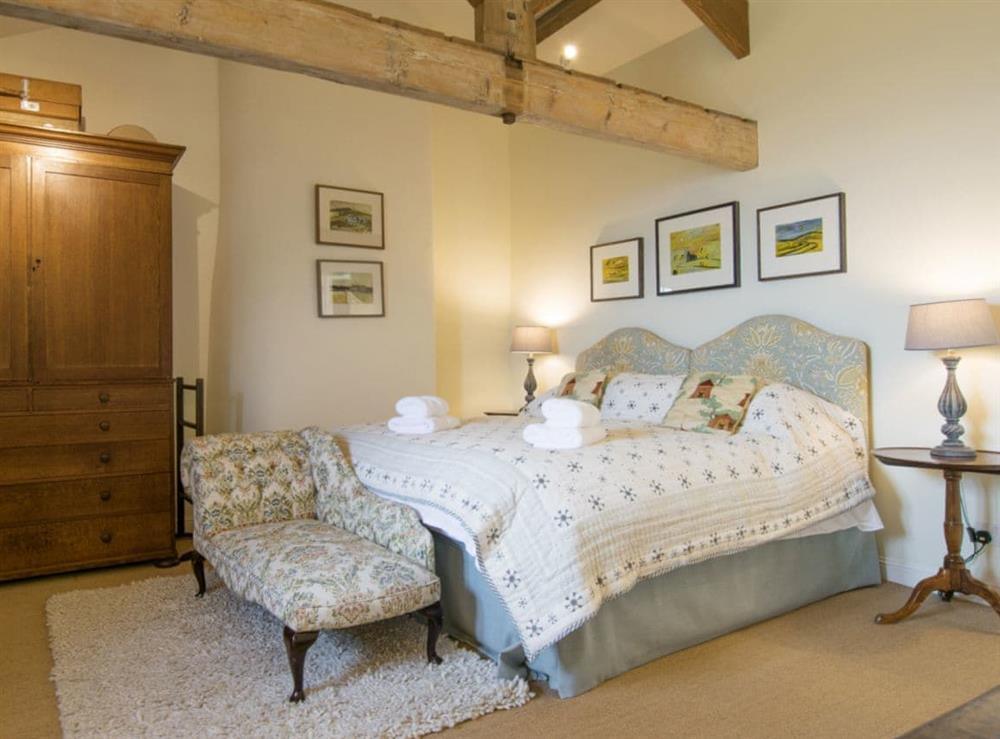 Master bedroom with exposed wood beams and en-suite bathroom at Higher Scarcliffe in Broughton, near Skipton, North Yorkshire