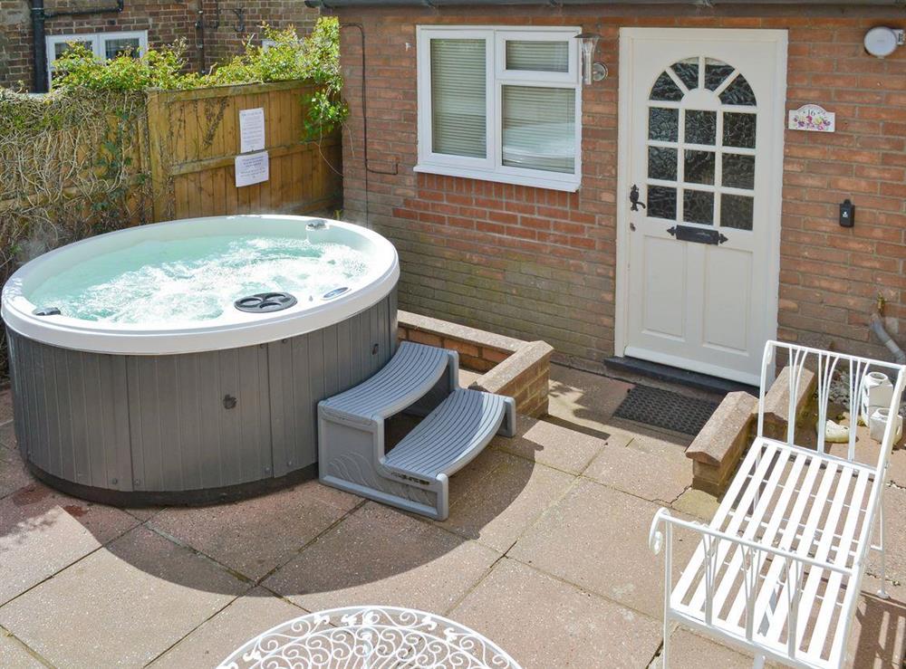 Hot tub and sitting out area within front courtyard at Hill Cottage in Holt, Norfolk