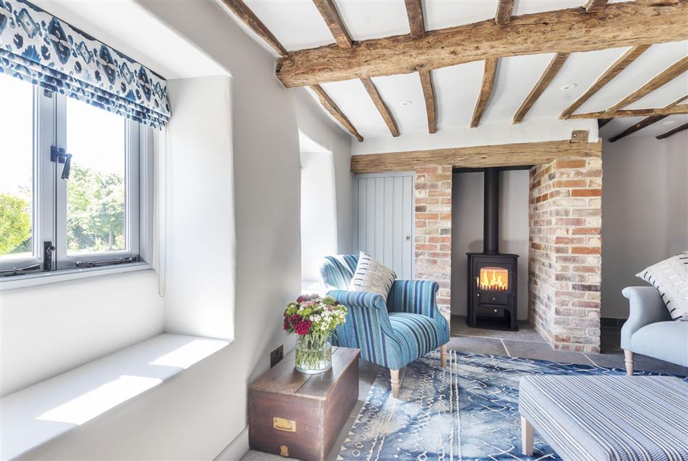 The sitting room with its characterful beams and the wood burning stove at Hilltop Cottage, Wimborne