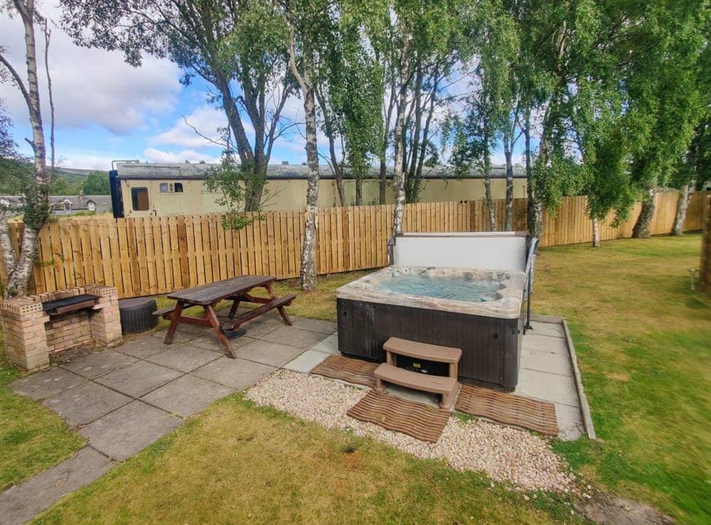 Garden area with hot tub at Holly Lodge in Aviemore, Highland, Inverness-Shire