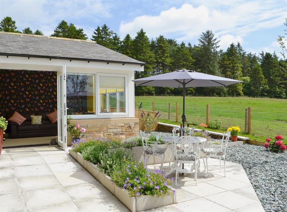 Paved garden with sitting-out area and garden furniture at Squirrel Cottage, 