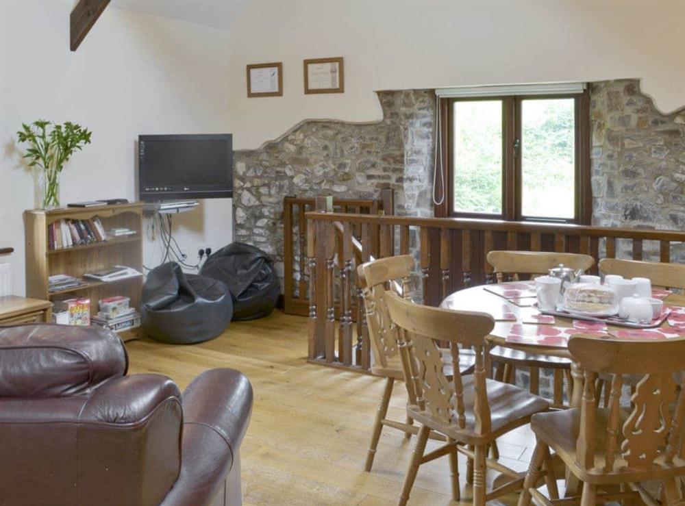 Cosy open-plan living space with wooden beams and wood floor at Homeleigh Barn in Poundstock, Bude, Cornwall
