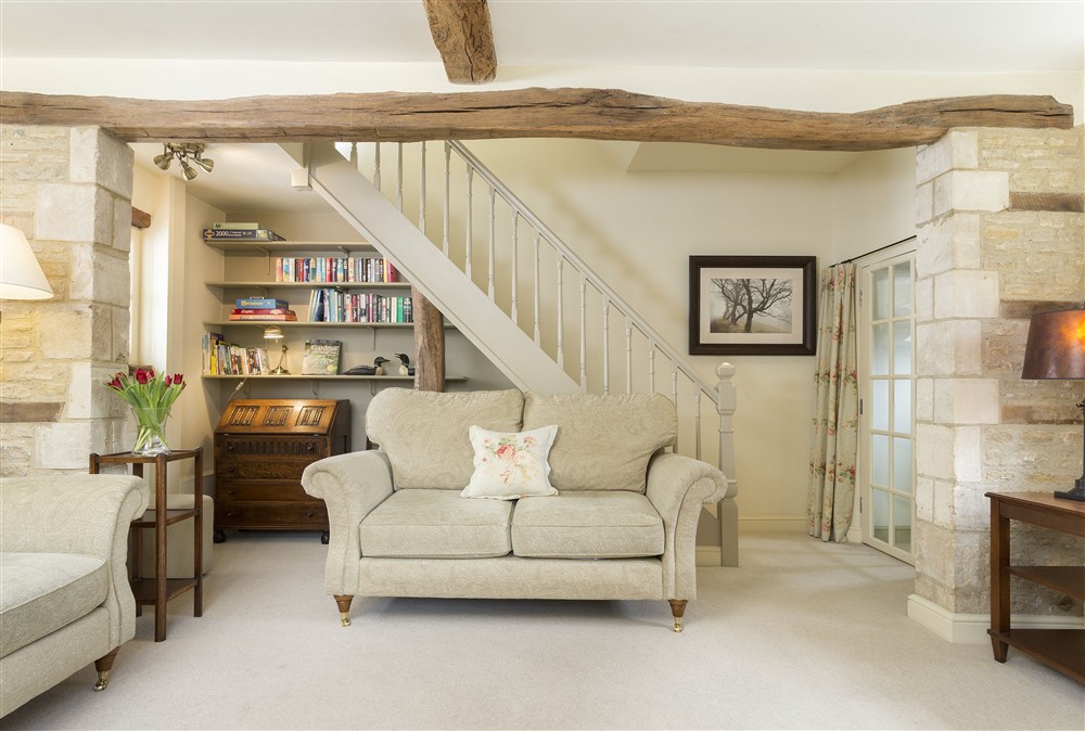 The calming sitting room with exposed beams and a wood burning stove at Hope Cottage, Quenington