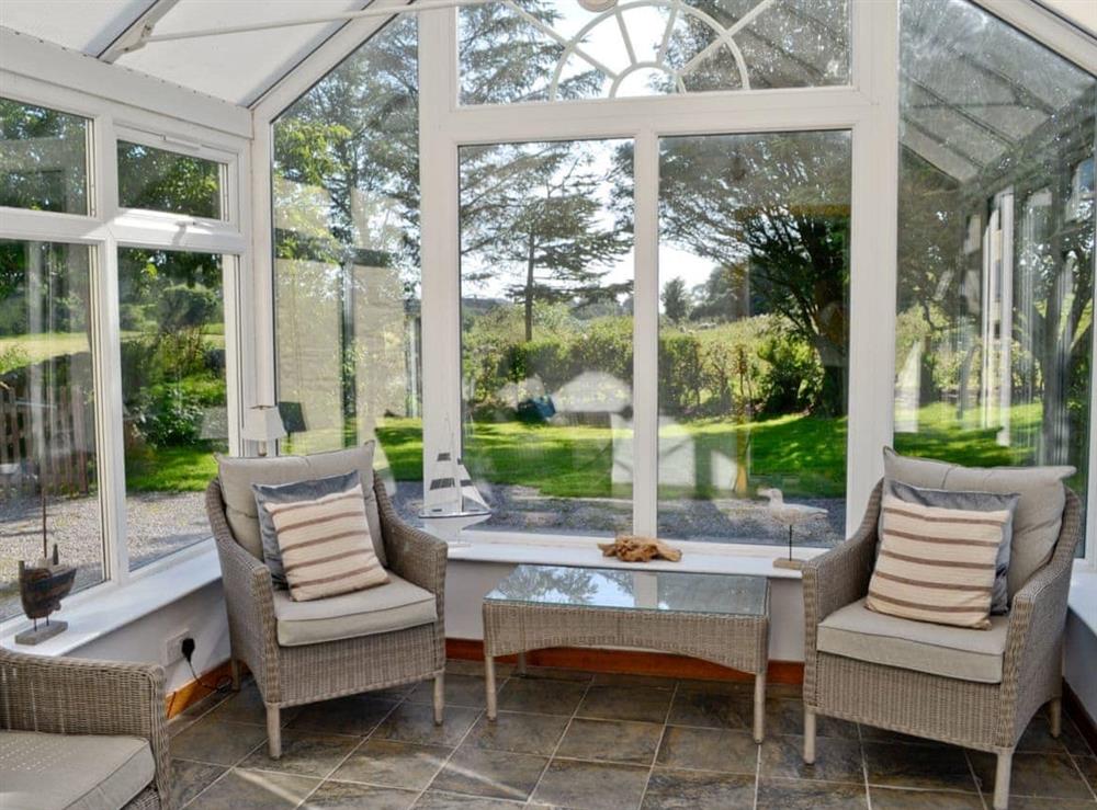 Relax in the sunny conservatory which overlooks the garden at Horsepark Cottage in Gatehouse of Fleet, Kirkcudbrightshire