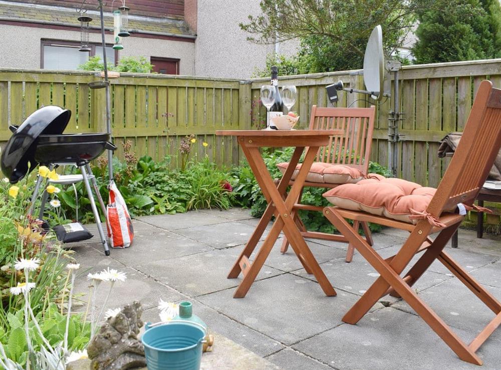Paved patio area with outdoor furniture and BBQ at Horseshoe Cottage in Freuchie, near Cupar, Fife