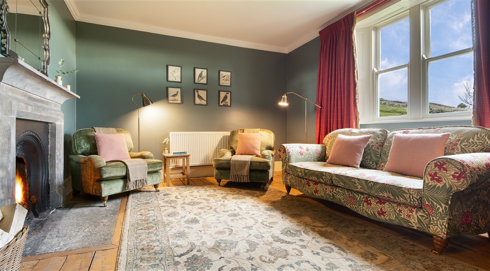 The sitting room with stone fireplace and open fire at Housesteads in Hexham, Northumberland