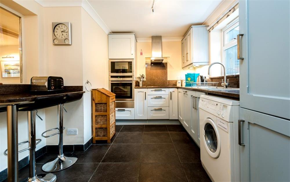 The kitchen is decorated in a calming blue tone and has mostly integrated appliances, including a full size fridge/freezer.  at Hove To in Helford Passage