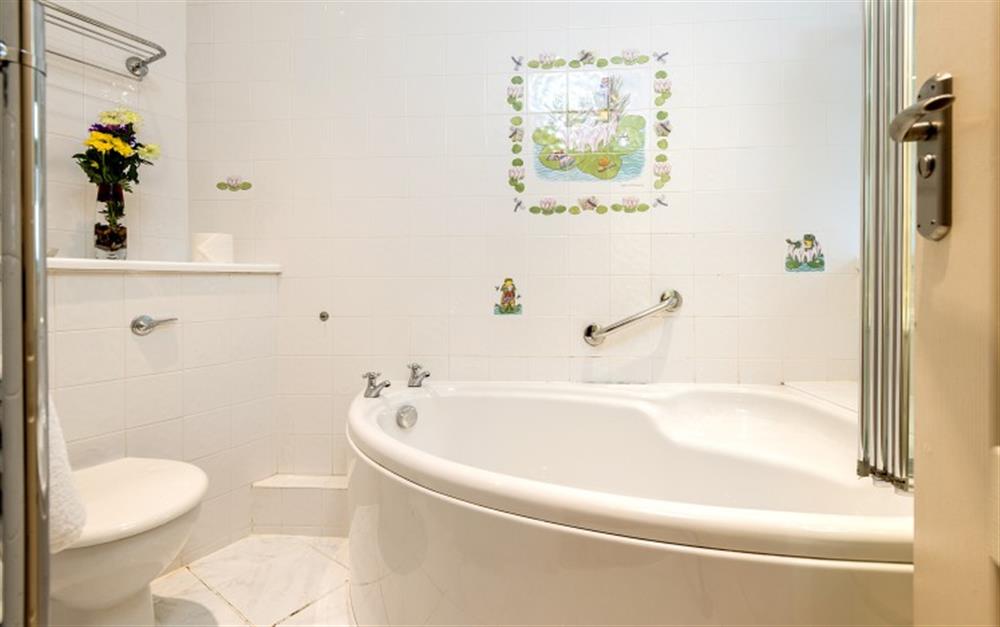 The main bathroom has a corner bath with a shower over the bath at Hove To in Helford Passage