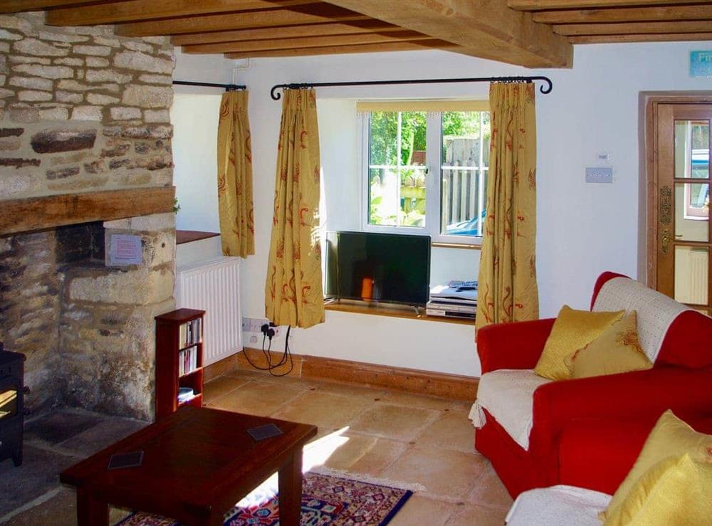 Charming living room with exposed stone fireplace at Ivy Cottage in Chedworth, near Cheltenham, Gloucestershire