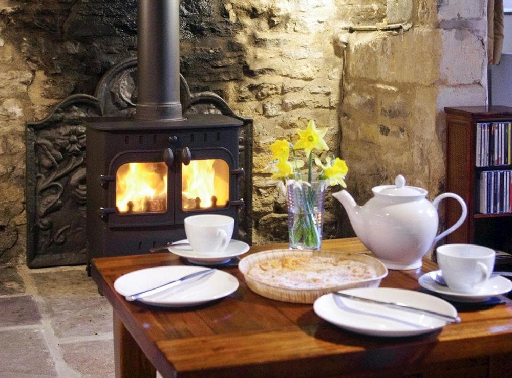 Warm and inviting room with stone fireplace, heritage features and wood burning stove at Ivy Cottage in Chedworth, near Cheltenham, Gloucestershire