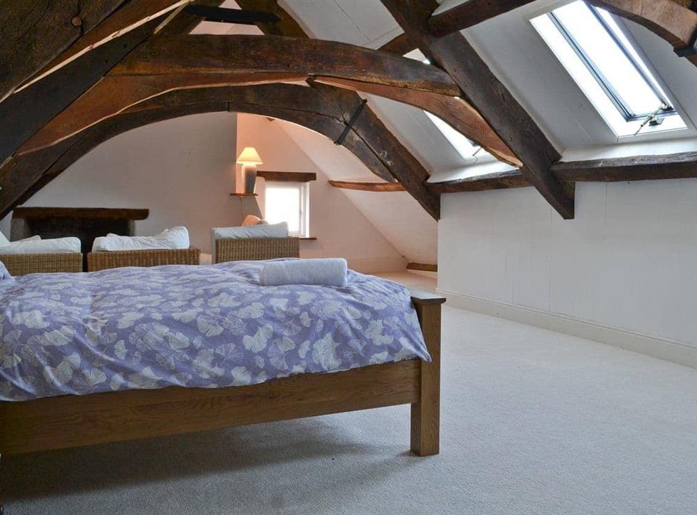 Double bedroom with beamed sloping ceiling & seating area at Jalna in Stratton, near Bude, Cornwall